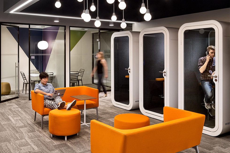 Mitarbeiterin führt privates Telefongespräch in einer schalldichten Telefonbox